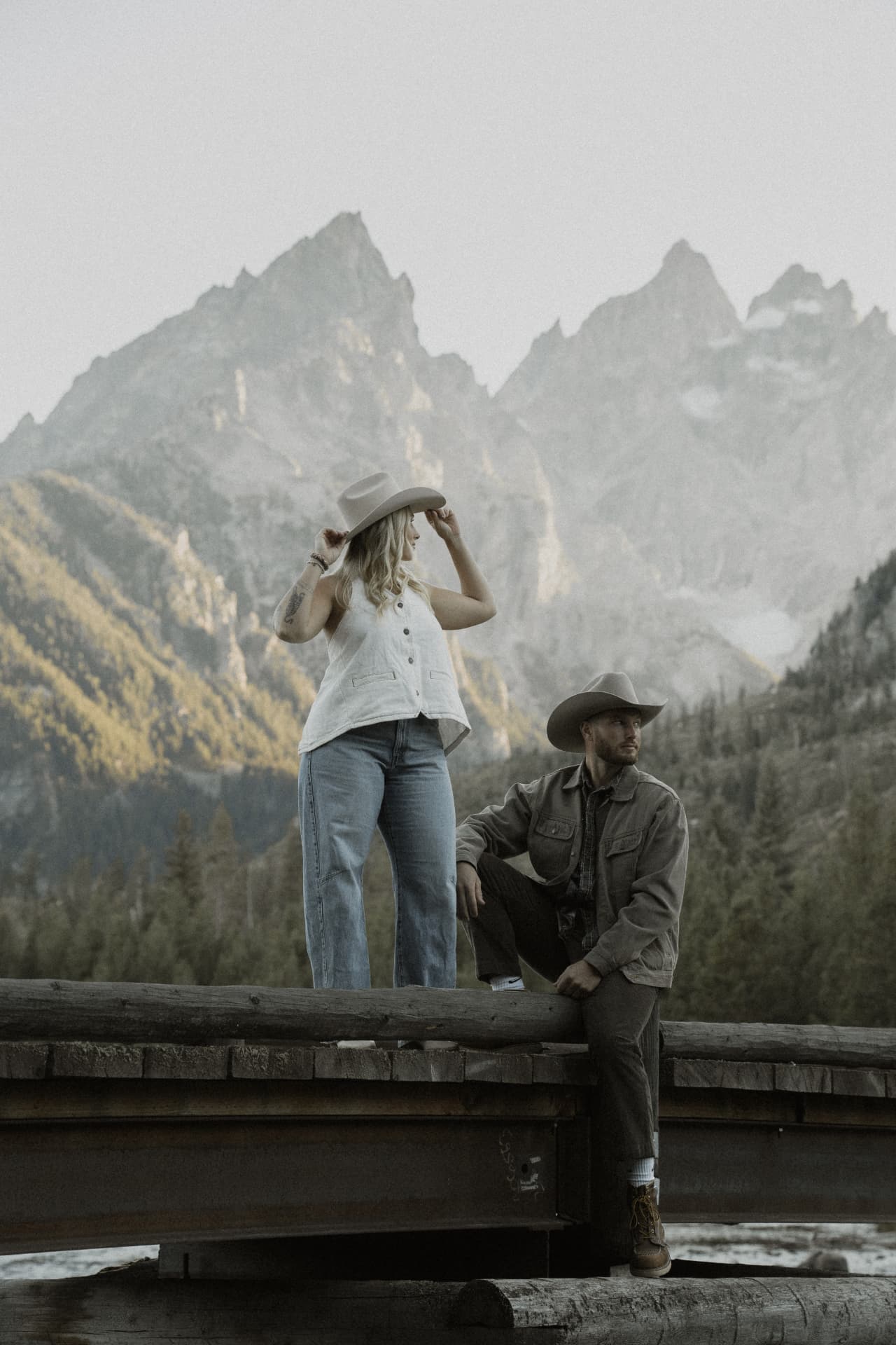 A couple beside a wooden fence beneath the Grand Tetons