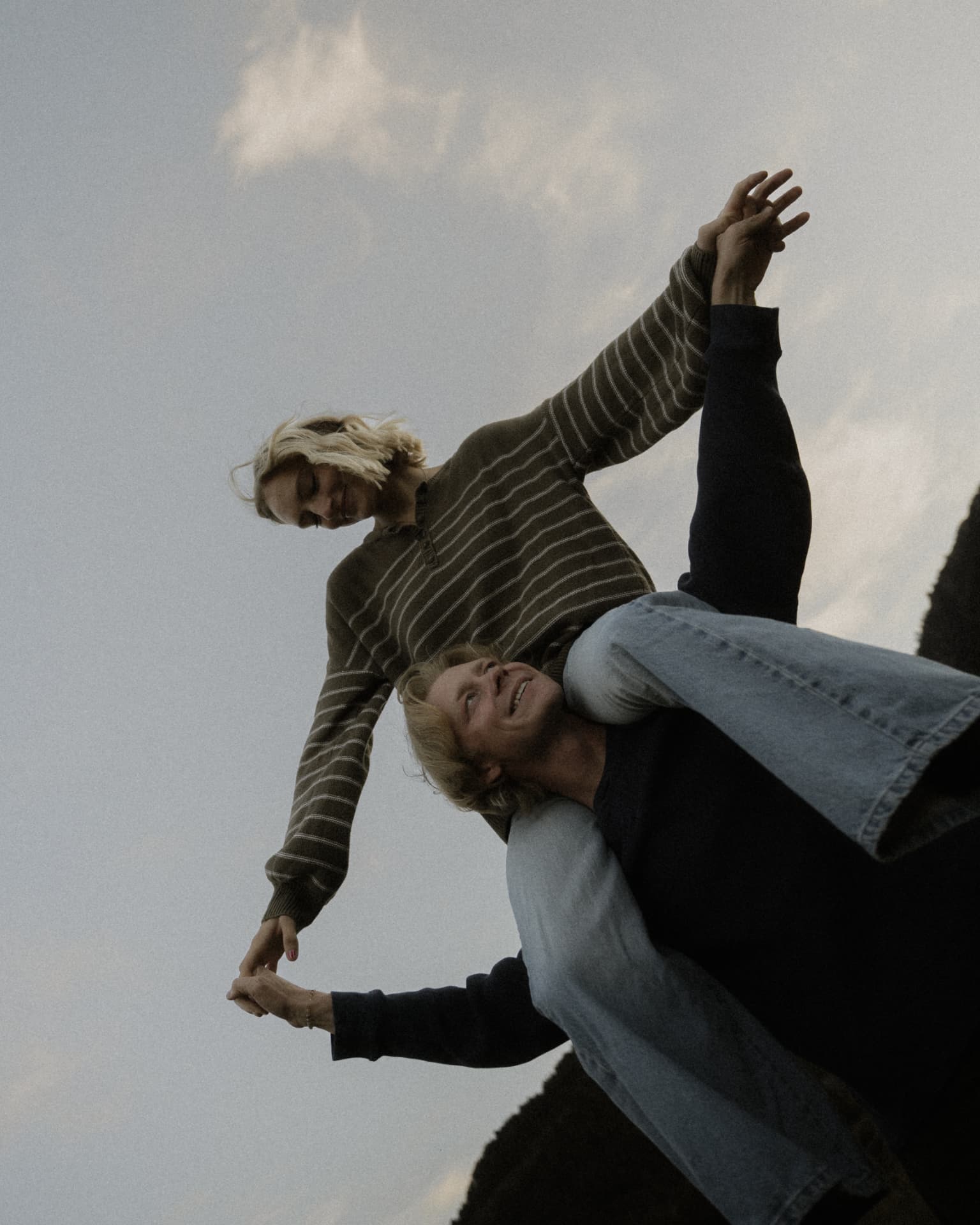 A laughing couple playing together beneath an open sky