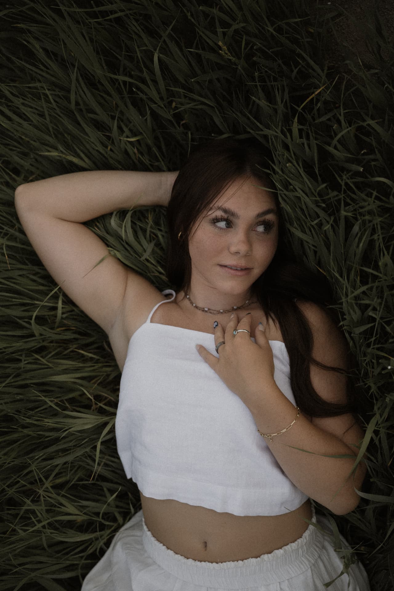 A woman lying back in tall grass in white