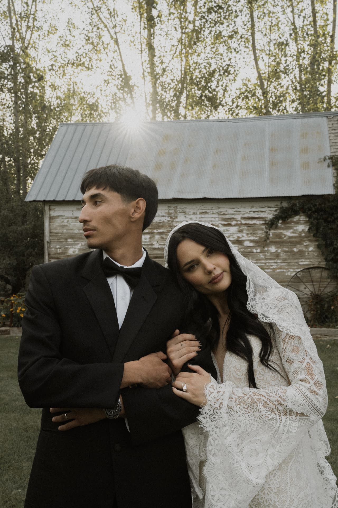 A bride leaning on the groom’s shoulder beside a rustic cabin