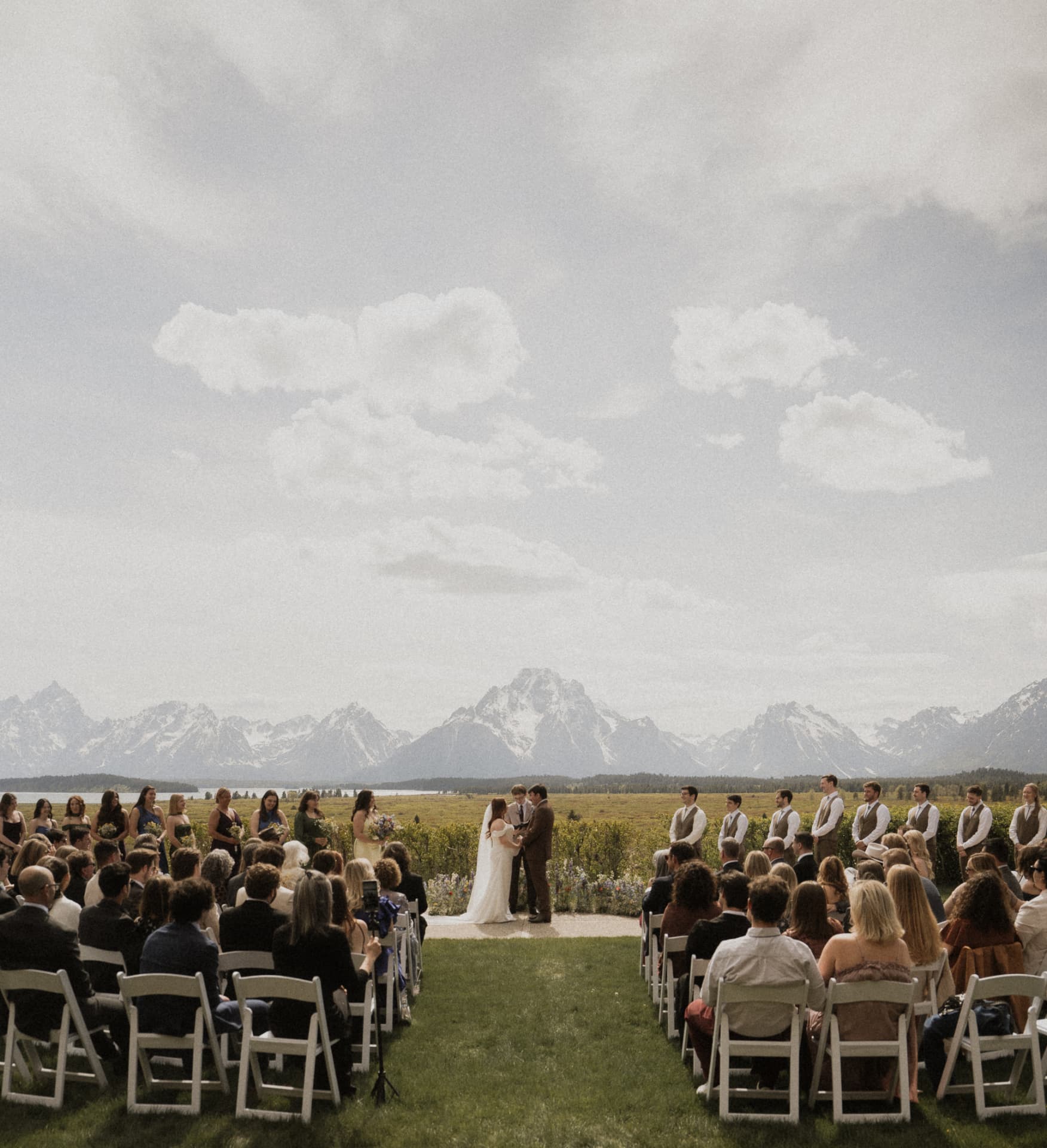 An outdoor wedding ceremony on a lawn beneath the Grand Tetons